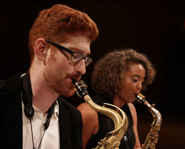 2 people playing saxophone